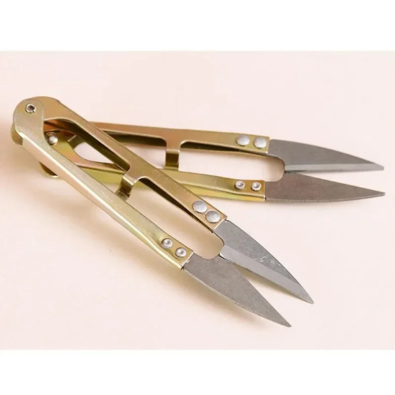 A pair of U-shape sewing scissors with silver blades and gold handles for cutting thread and fabric.
