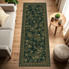 A long, dark green vintage botanical runner rug with gold accents placed on a light wood floor.