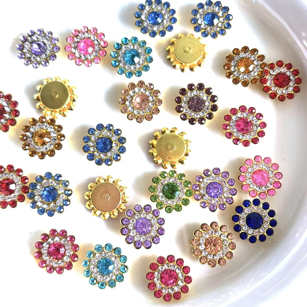 A collection of multicolor sew-on rhinestone crystals in various shades of pink, blue, and gold arranged on a white surface.