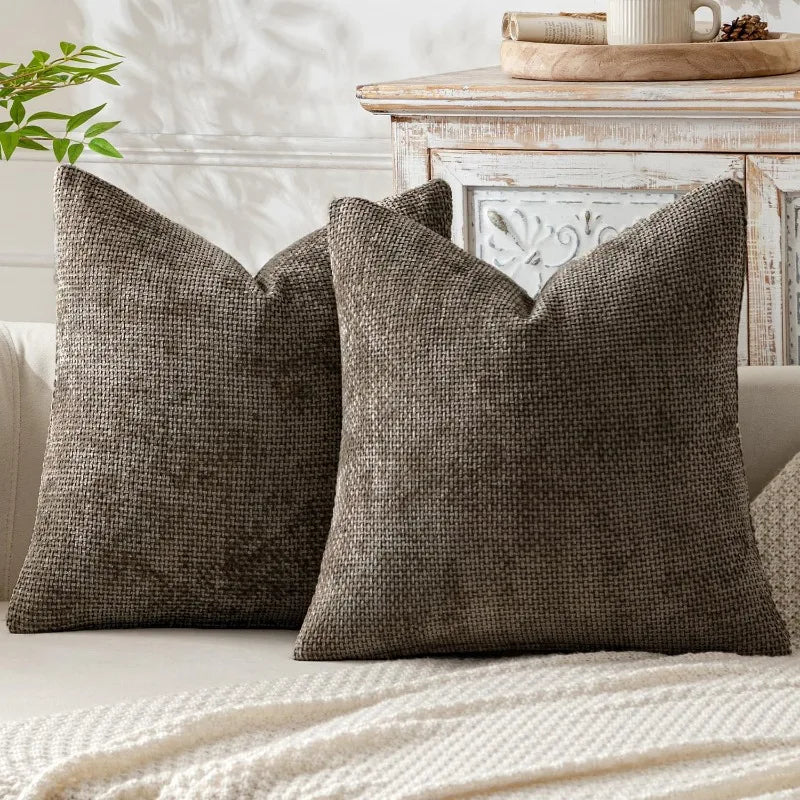A dark olive green textured pillow resting on a light-colored sofa next to a wooden table.