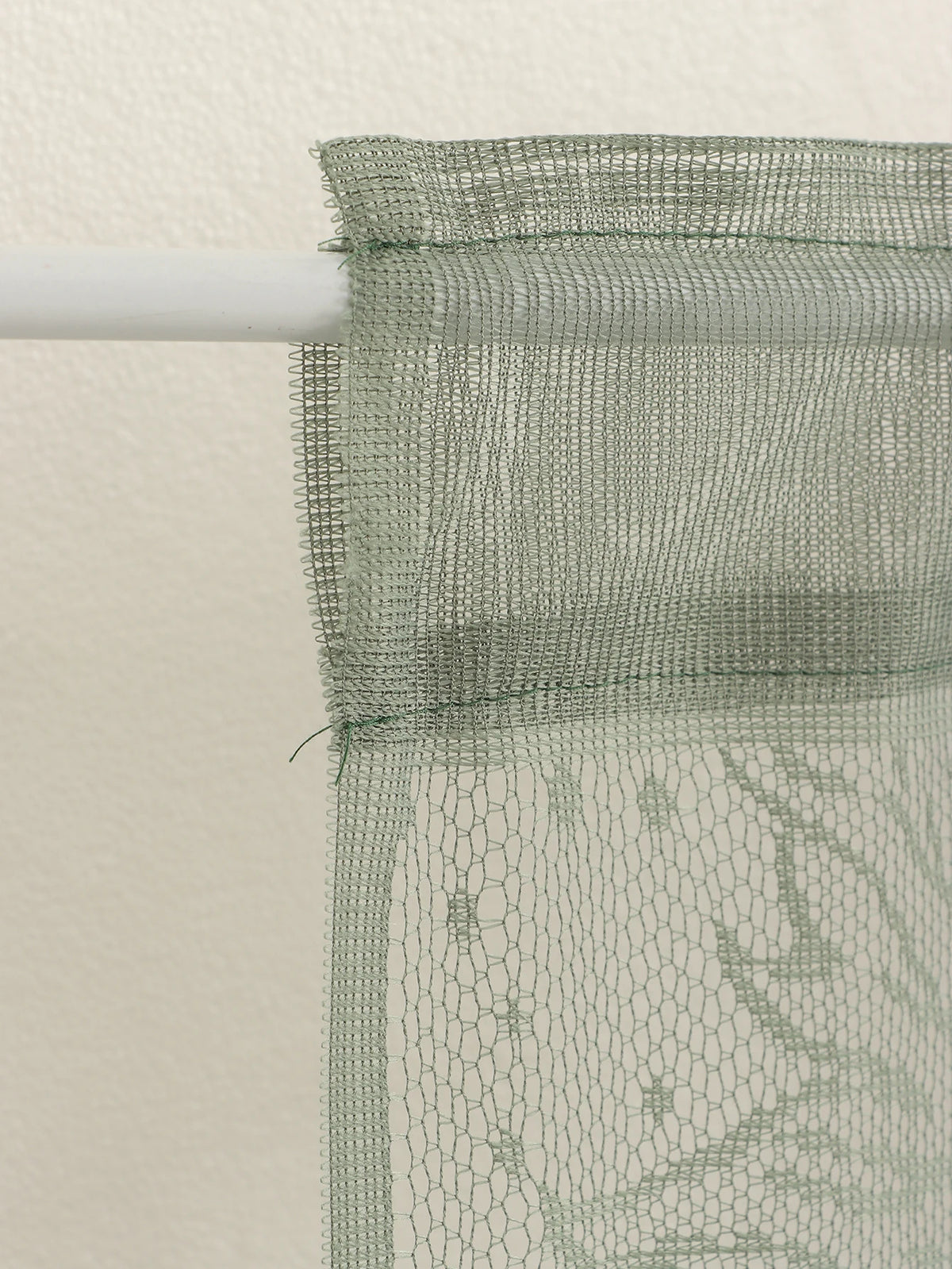 Translucent sun and moon lace door curtain draped over a white rod.