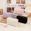 A collection of pink, purple, and black luxury velvet cosmetic storage pouches displayed in front of a sign.