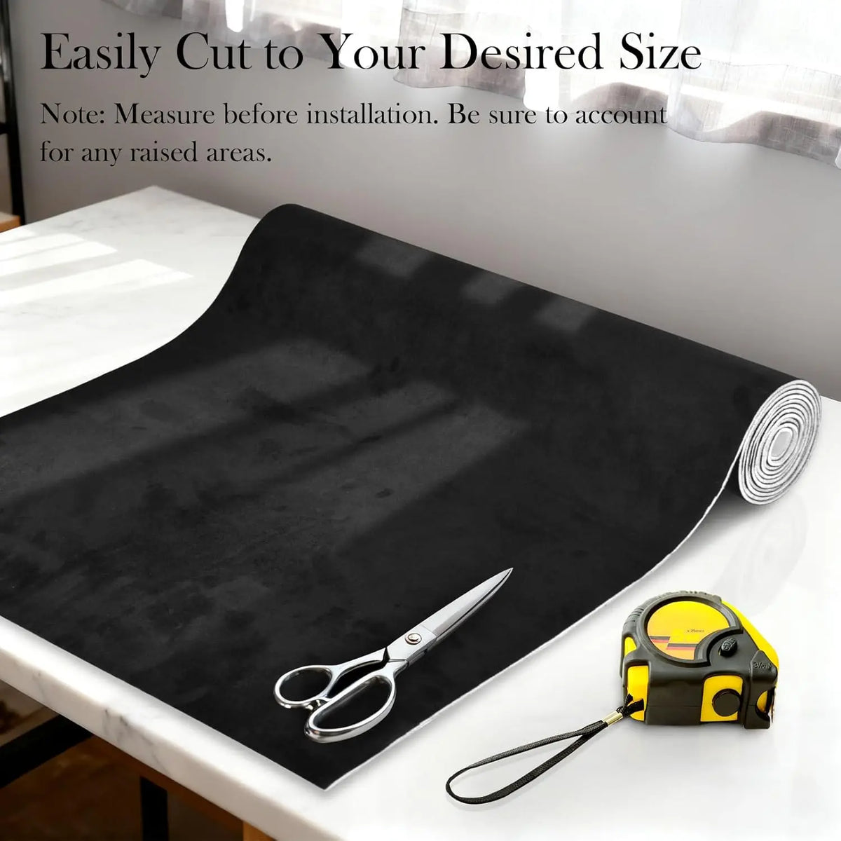 Black suede auto headliner fabric roll next to a pair of scissors for cutting