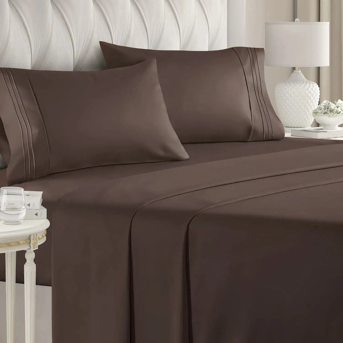 A set of brown microfiber bed sheets and pillows with a gathered design on a bed.