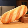 A loaf of golden-brown French bread with striped scoring is shown resting on a wooden surface.