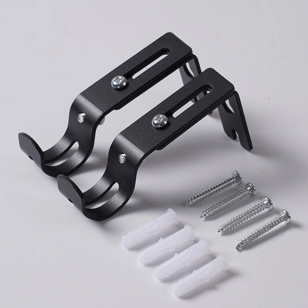 A black adjustable iron curtain rod rack with mounting brackets and screws is shown on a white background.