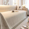 A beige elegant jacquard sofa cover blanket draped over a light-colored sofa with white pillows and natural light.