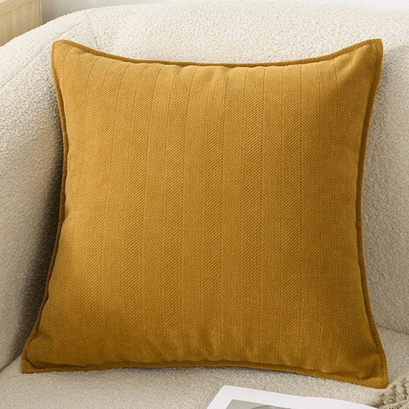 A mustard yellow chenille throw pillow cover resting on a light beige sofa cushion.