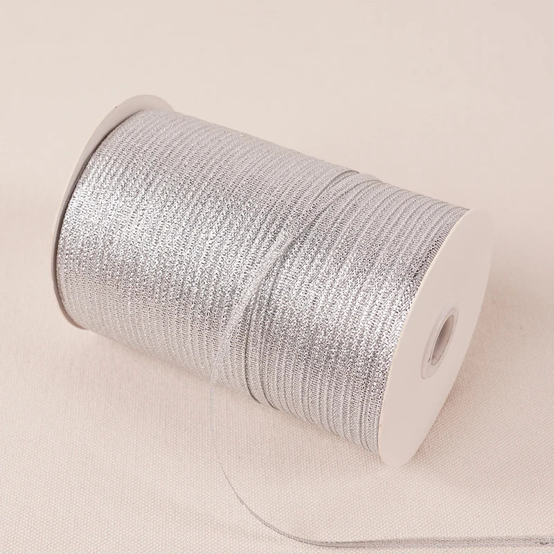 A roll of 10-meter gold and silver glitter satin ribbon with a white core and thin string attached.