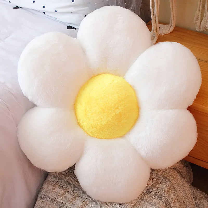 A white and yellow sunflower plush flower cushion resting on a wooden surface.