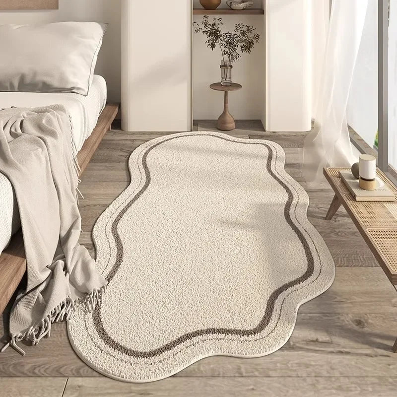 A beige irregular plush area rug with subtle brown edging placed on a light wood floor.