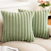 A pair of light green faux rabbit fur cushion covers resting on a beige sofa.