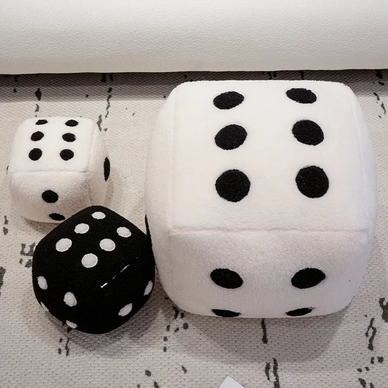 A set of oversized black and white polka dot dice plush toys resting on a light surface.