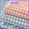 Pink and white checkered fitted sheet fabric rolled up, showing comfort and ultra-soft texture.