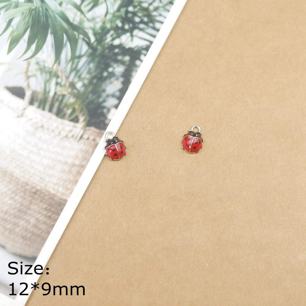 A set of two red ladybug resin charms with silver jump rings displayed on brown kraft paper.