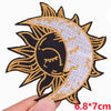 Gold and black embroidered sun and crescent moon patch on a fabric background