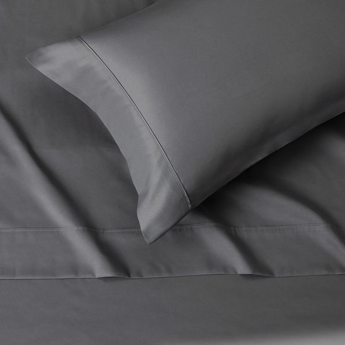 A close-up view of a smooth gray microfiber flat fitted sheet with a neatly folded corner.