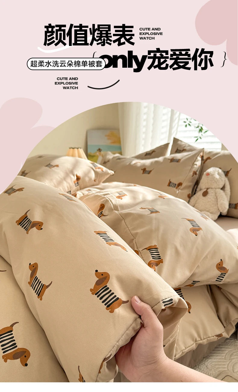 A close-up of a beige duvet cover featuring a cute dog print, being held by a hand.