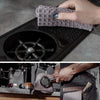 A hand is holding a gray lint-free microfiber cleaning towel over the portafilter of a coffee machine.
