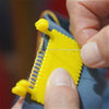 A hand is using a hinge-type fabric sewing guide with a measuring scale to mark fabric.