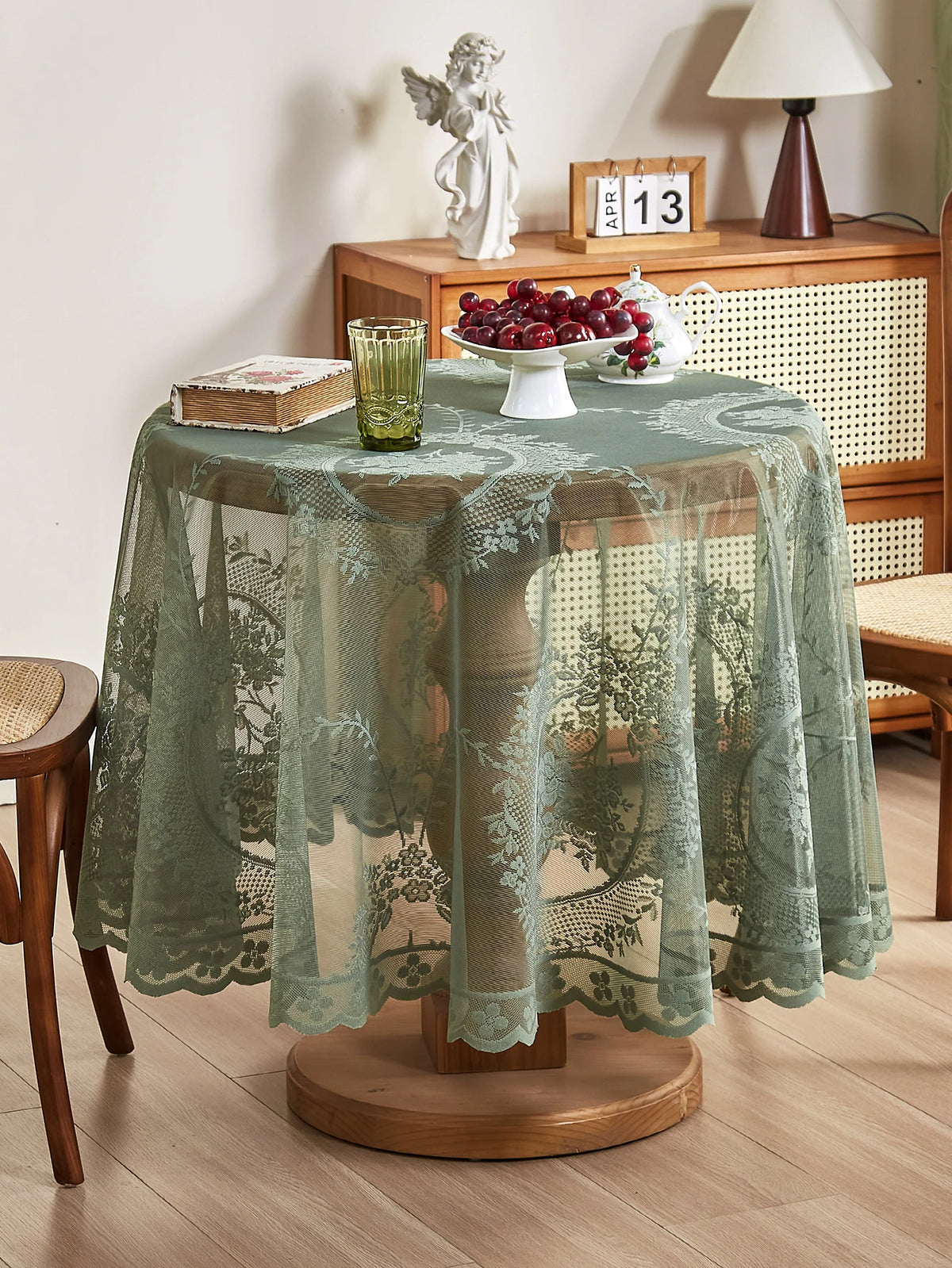 A round floral lace tablecloth with a tatting weave displayed on a wooden table.