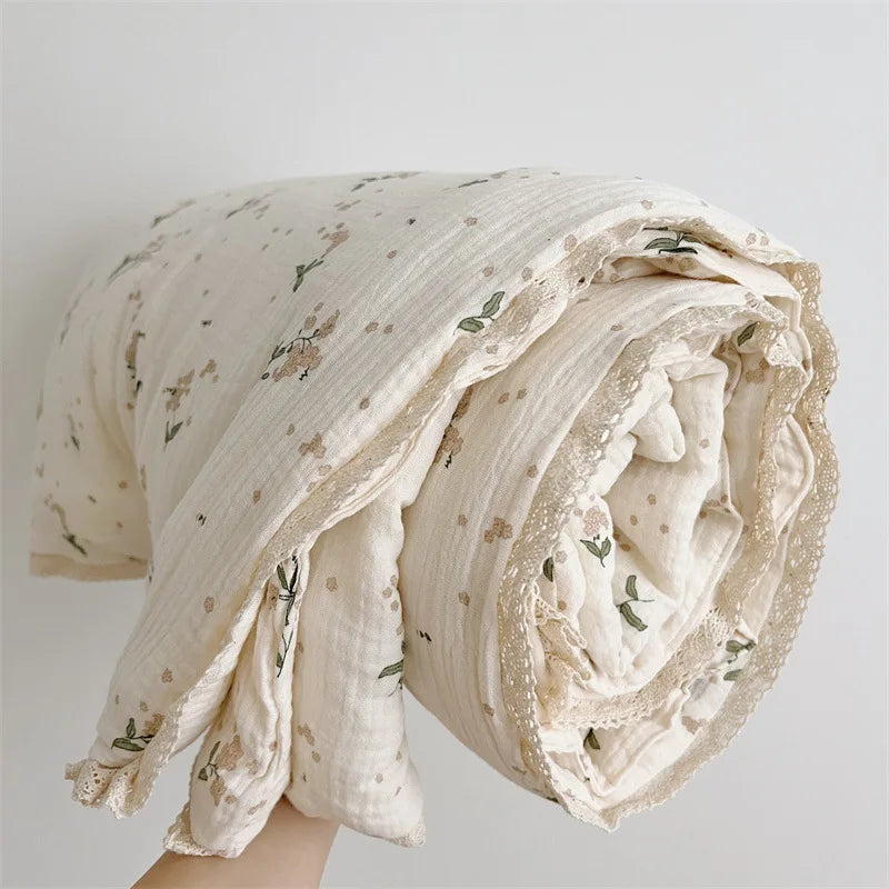 A rolled floral print muslin blanket in cream and green tones.