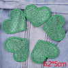 Five green glitter iron-on embroidered love heart star patches arranged on a gray denim fabric.