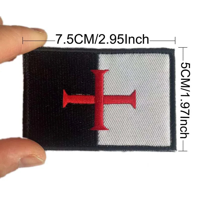 Black and white embroidered patch featuring a red cross on a flag design