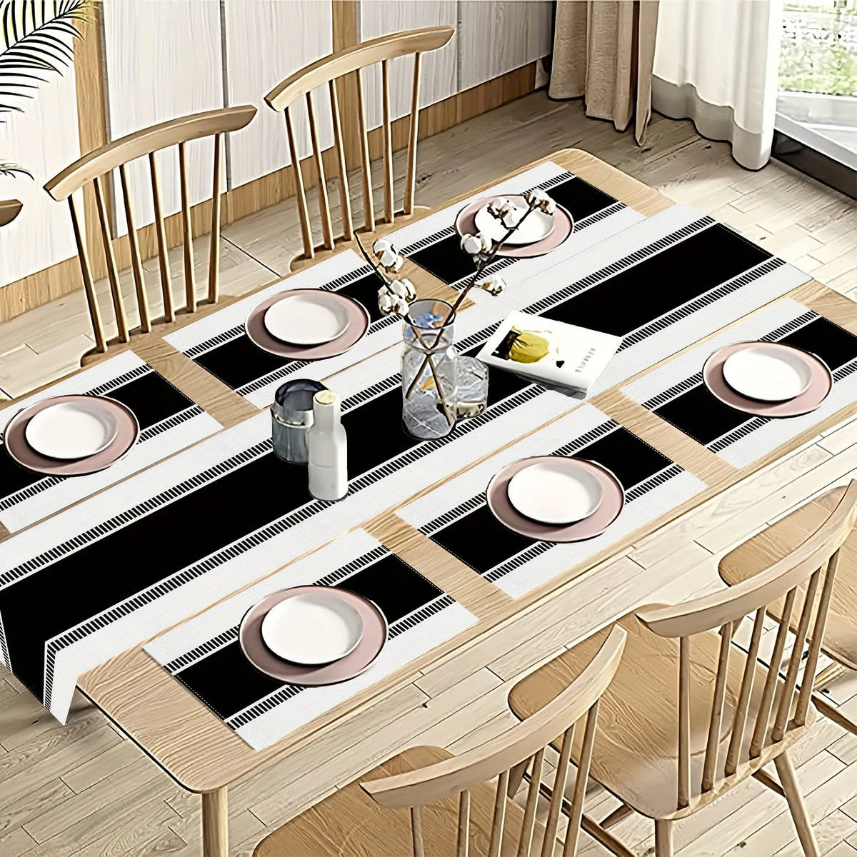 A set of minimalist black and white placemats and table flags laid out on a wooden table with dining chairs.