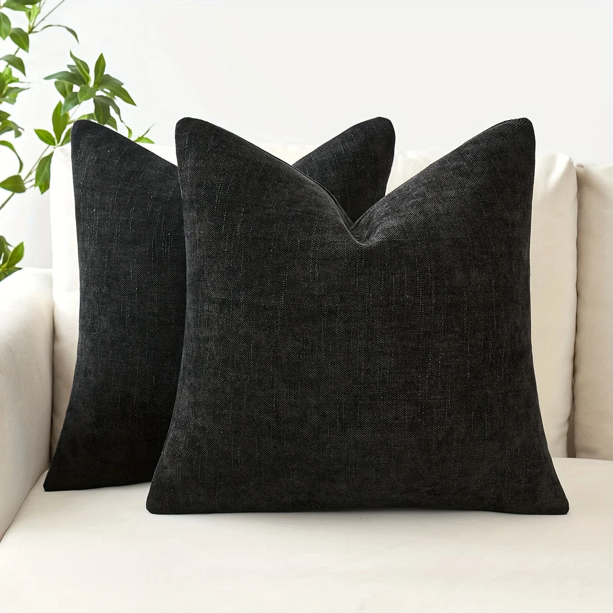 Three black linen textured throw pillows resting on a white sofa.