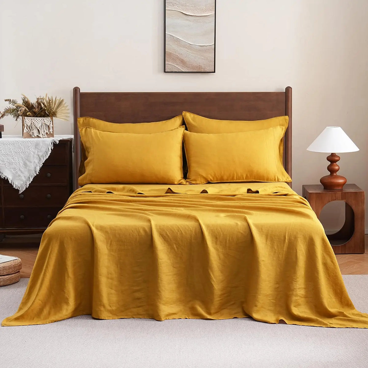 A luxurious golden yellow pure French linen bed sheet draped over a bed with wooden headboard and bedside lamp.
