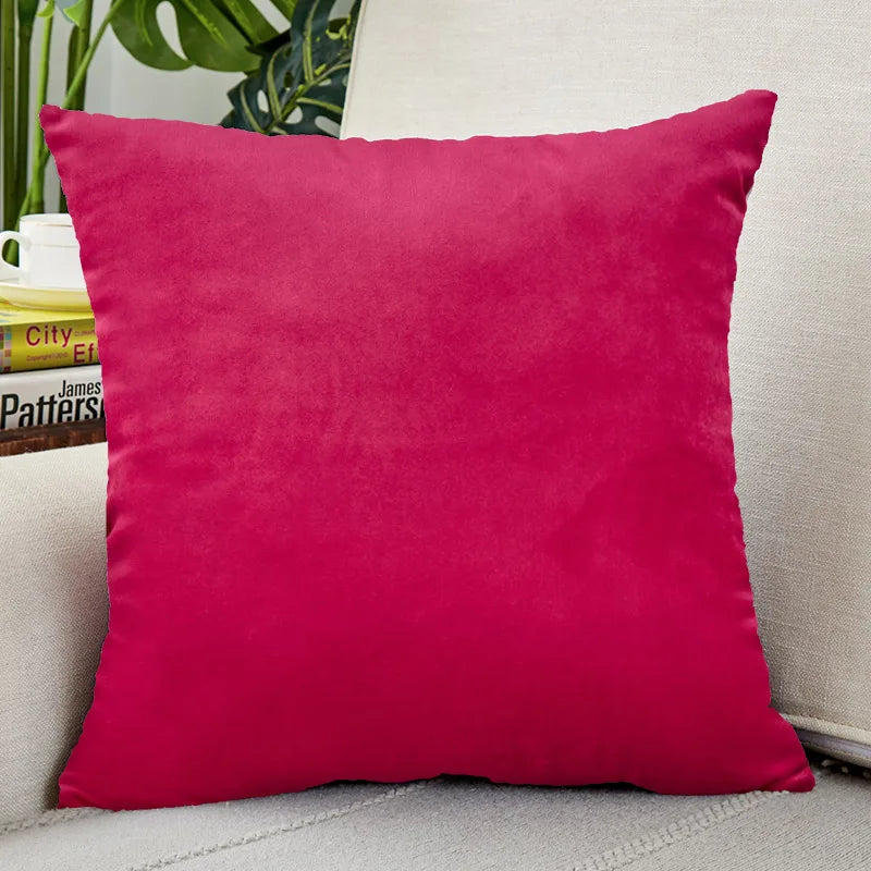A vibrant magenta velvet cushion cover resting on a light-colored surface.