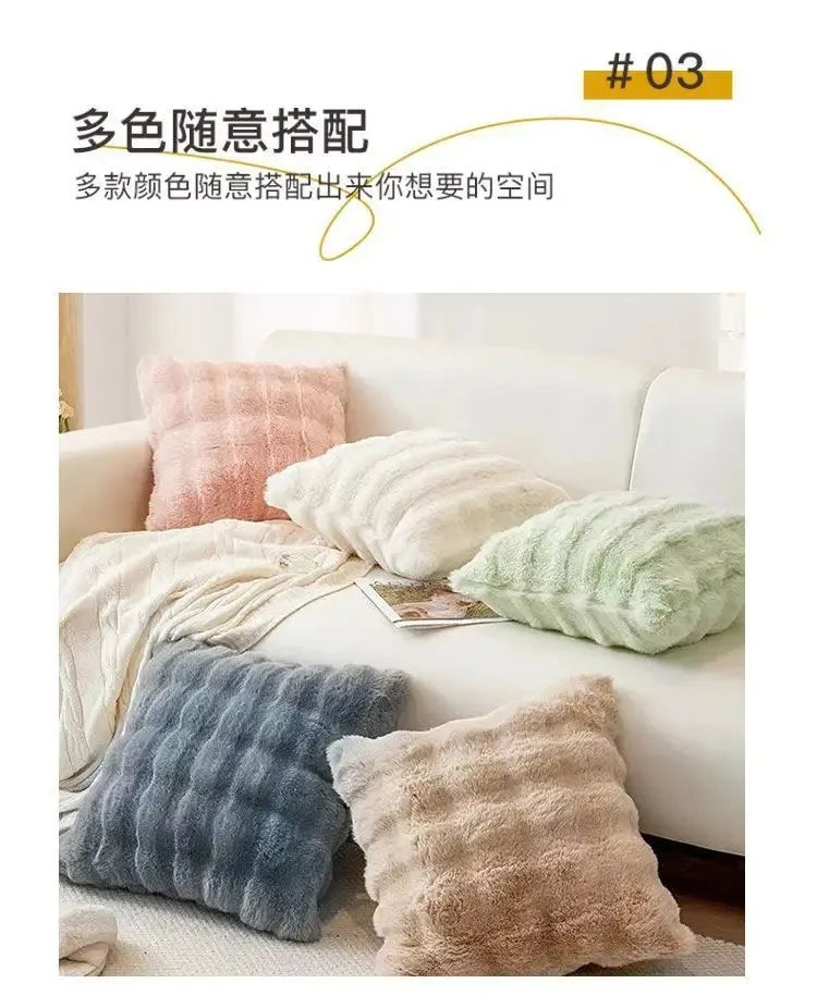 A collection of various colored plush winter throw pillows displayed on a white sofa.