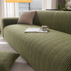 A moss green sofa slipcover with a textured weave sits in a bright living room setting.
