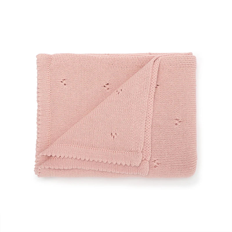 A folded pink super soft cotton knit baby blanket for infant sleep.