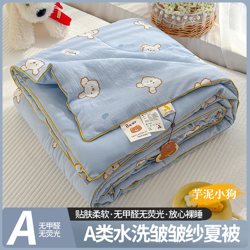 A lightweight summer quilt with a cartoon pattern featuring small bear shapes, folded and displayed on a white surface.