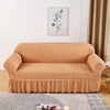 A tan stretch knit sofa cover featuring a bubble lattice texture placed on a wooden floor.
