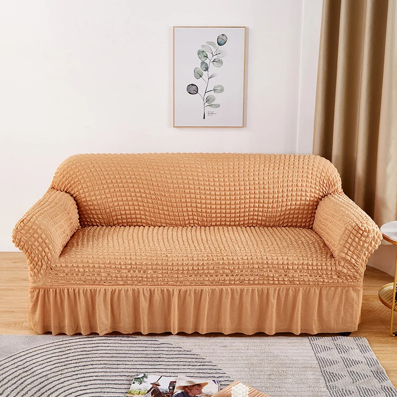 A tan stretch knit sofa cover featuring a bubble lattice texture placed on a wooden floor.