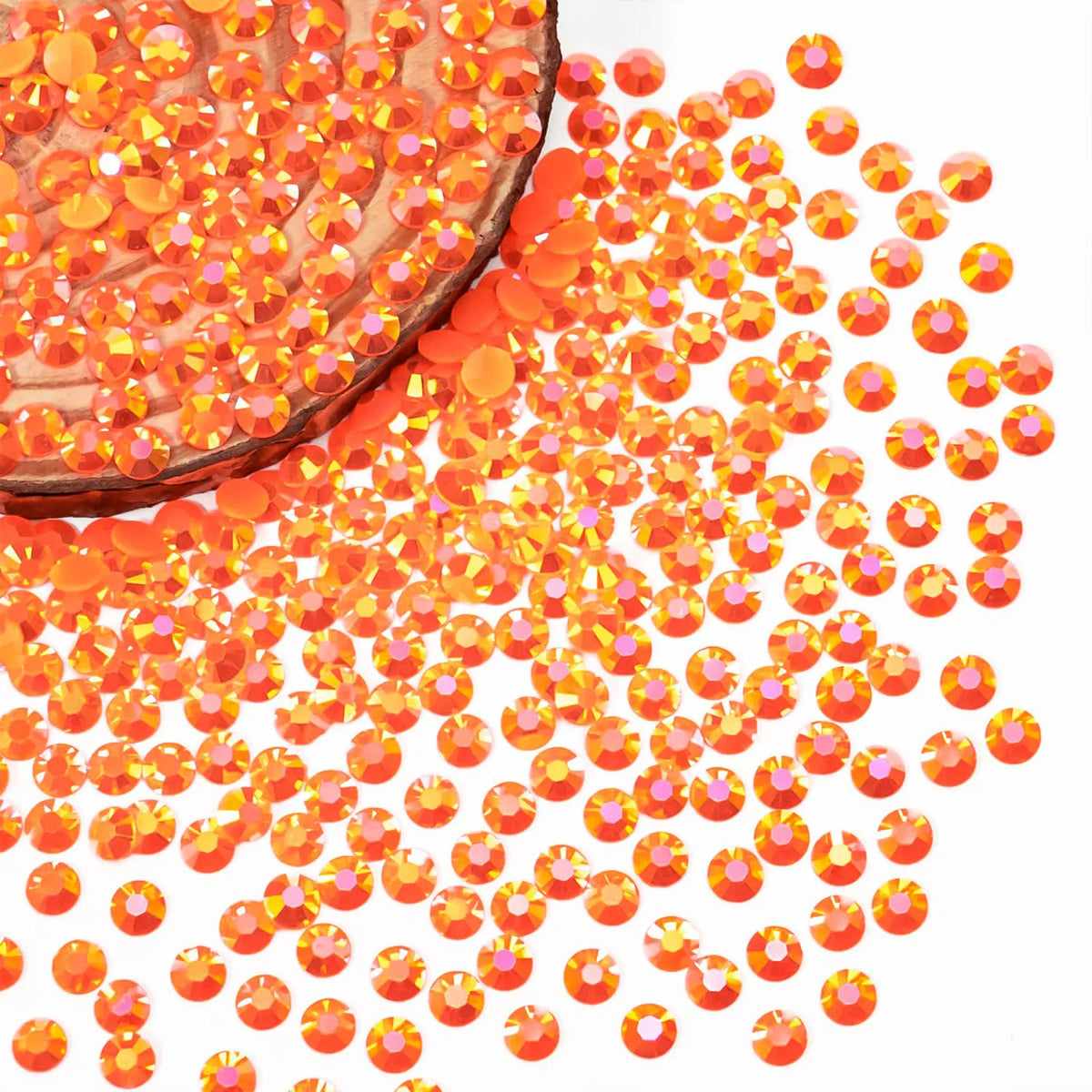 A close-up view of orange-red AB resin flatback rhinestones scattered on a white background.
