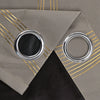 A silver grommet top curtain with a black fabric and gold striped fabric backing.