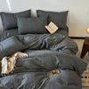 A gray cotton yarn-dyed duvet cover with matching pillows and a light wood book on a bed.