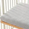 A soft gray plush mattress and diaper changing cover placed on a wooden crib rail.