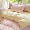A pink and white checkered duvet cover set with matching pillows on a bed near a window.