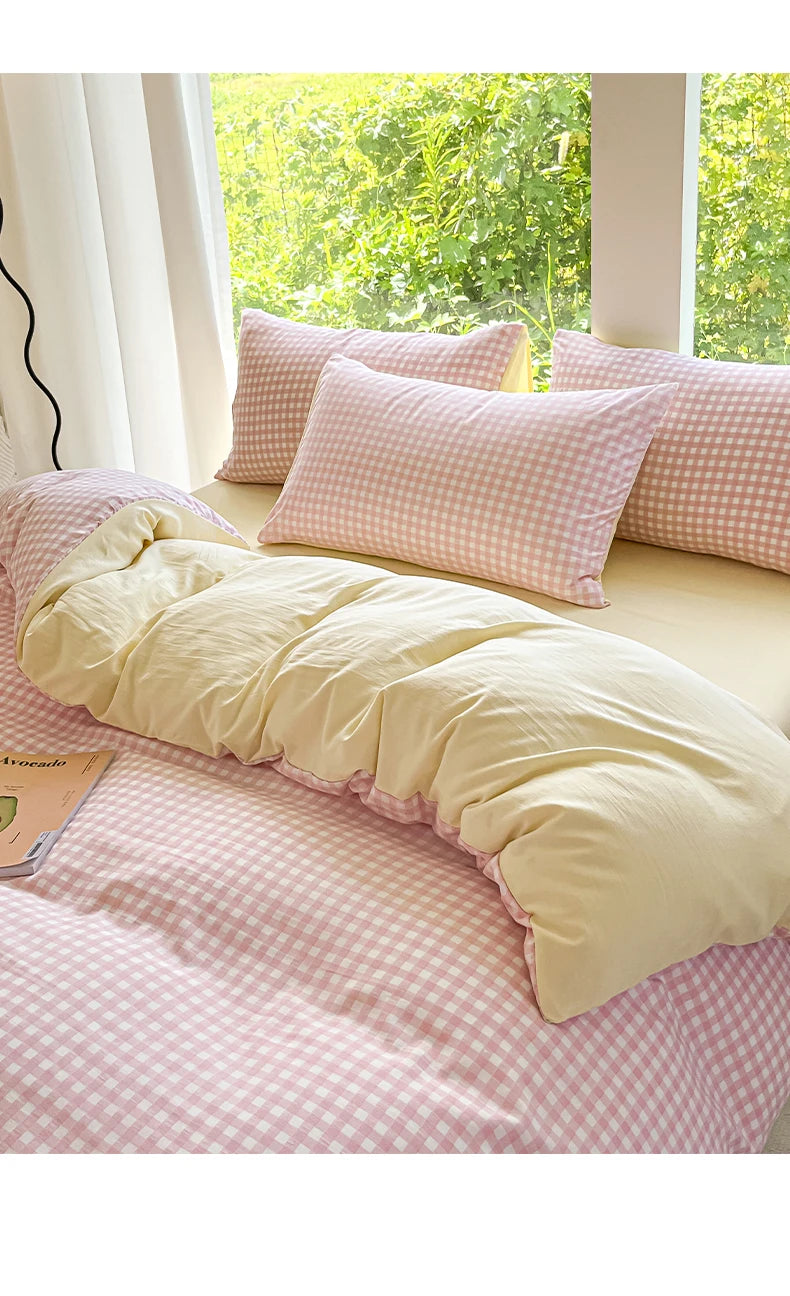 A pink and white checkered duvet cover set with matching pillows on a bed near a window.