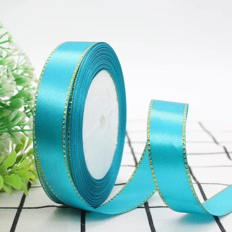 Roll of turquoise satin ribbon with gold edges for gift wrapping and crafts