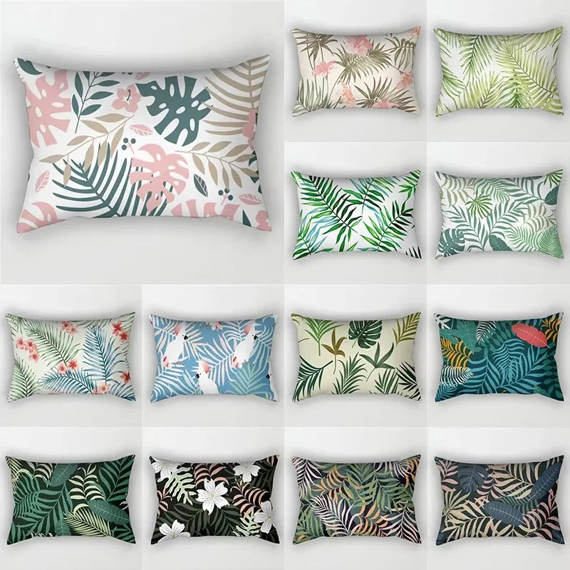 A collection of nine decorative pillows featuring various tropical leaf prints in shades of green, pink, and beige.
