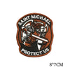 A dark brown embroidered patch featuring the text SAINT MICHAEL PROTECT US on a circular background.