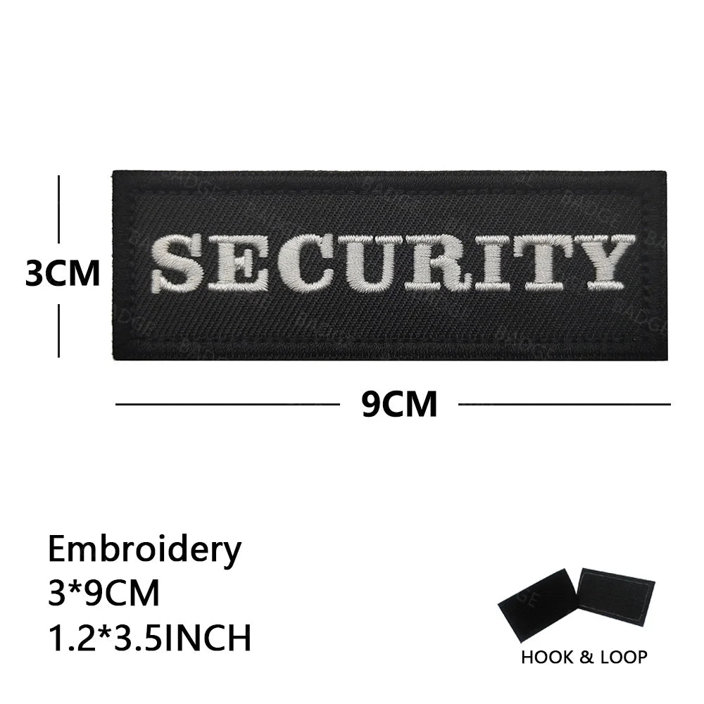 Black embroidered security patch measuring 3cm by 9cm with hook and loop backing