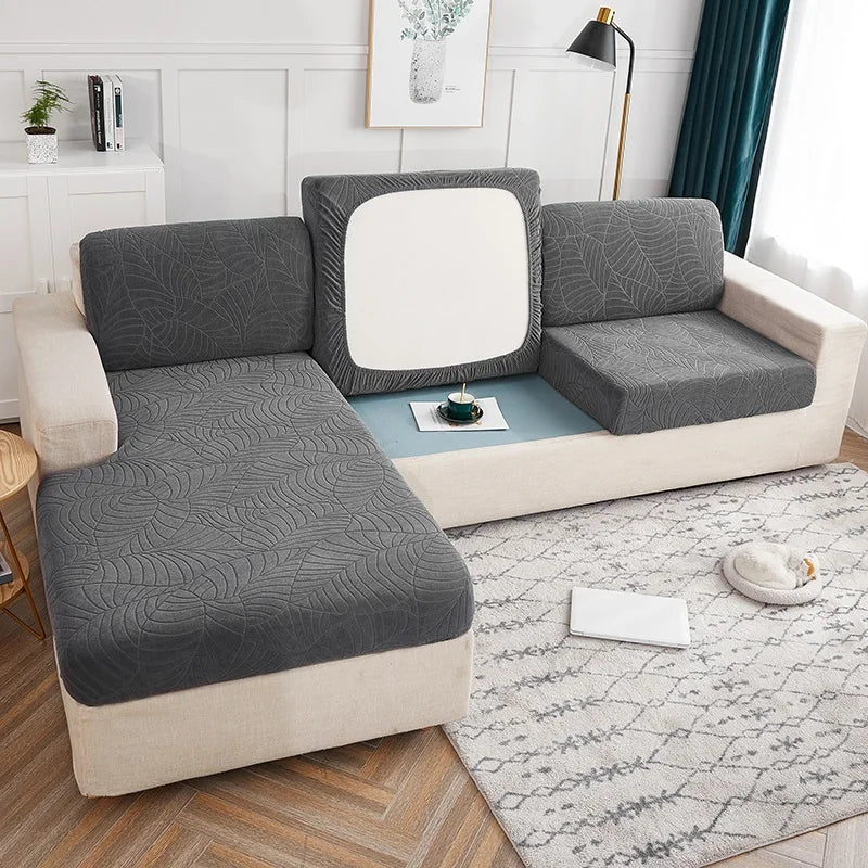 A gray waterproof jacquard stretch sofa cover displayed on a light-colored sofa in a modern living room.