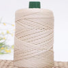 A spool of beige crochet ice rope with a green cap resting on a woven mat.